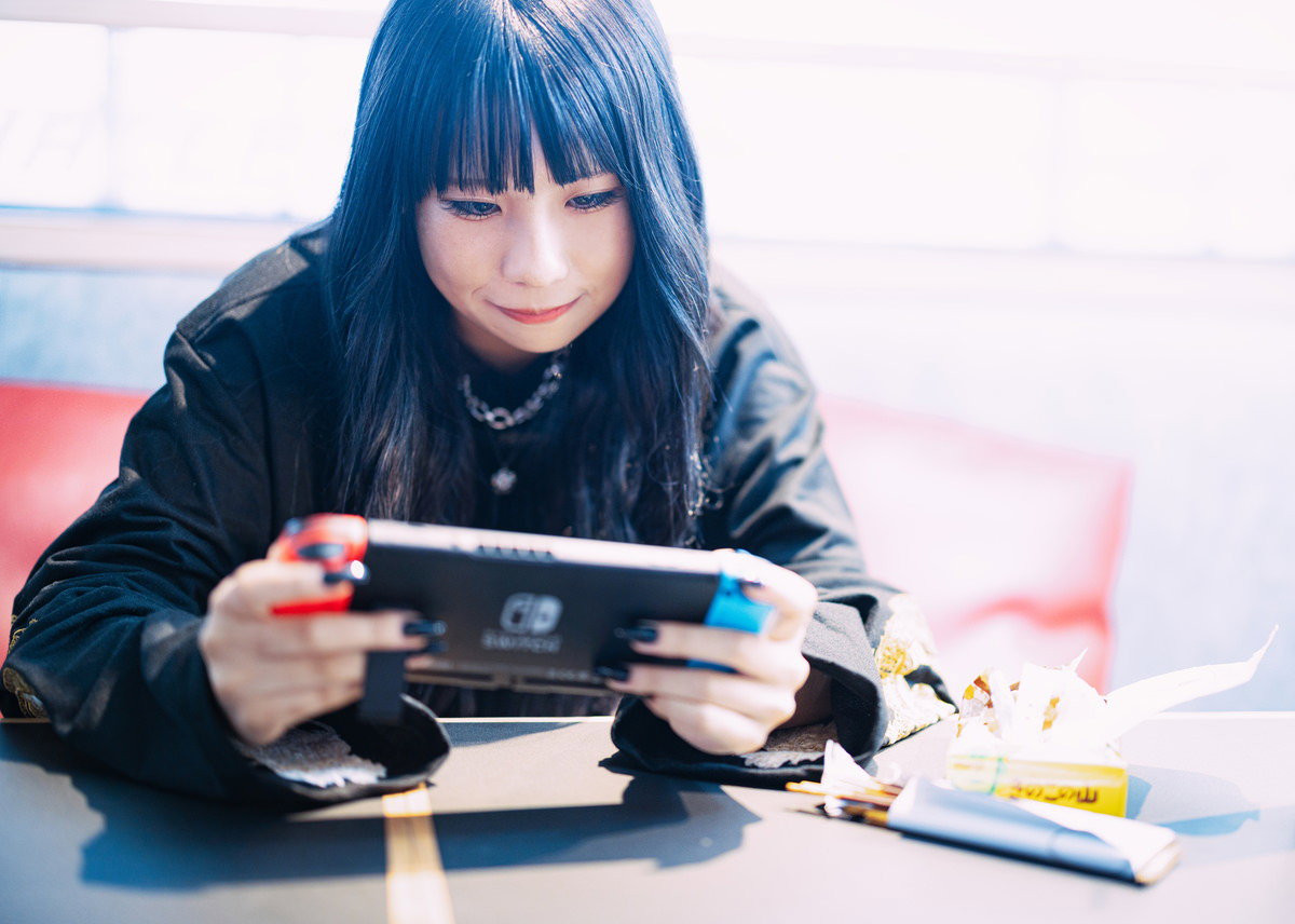 くつろぎながら携帯ゲームに熱中する女性の無料写真素材