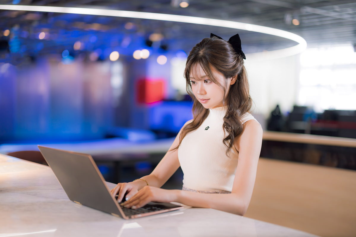 カフェエリアでリラックスしながらPC作業をする女性の無料写真素材