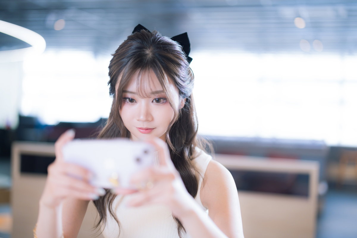 カフェエリアでスマホゲームを楽しむ女性の無料写真素材