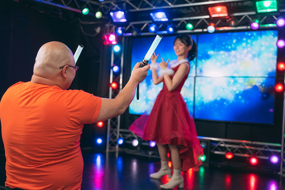 推しのアイドルイベントでペンライトを振る男性