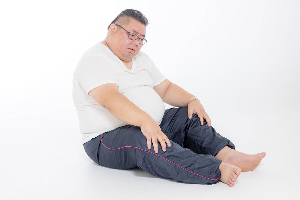 お腹の肉が邪魔でうまく座れない男性