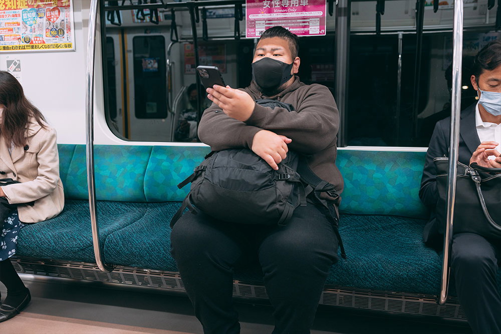 電車の席に座る160キロの男性