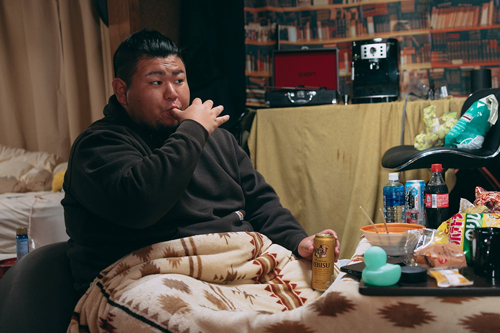 手についた食べ残りを舐めるデブ
