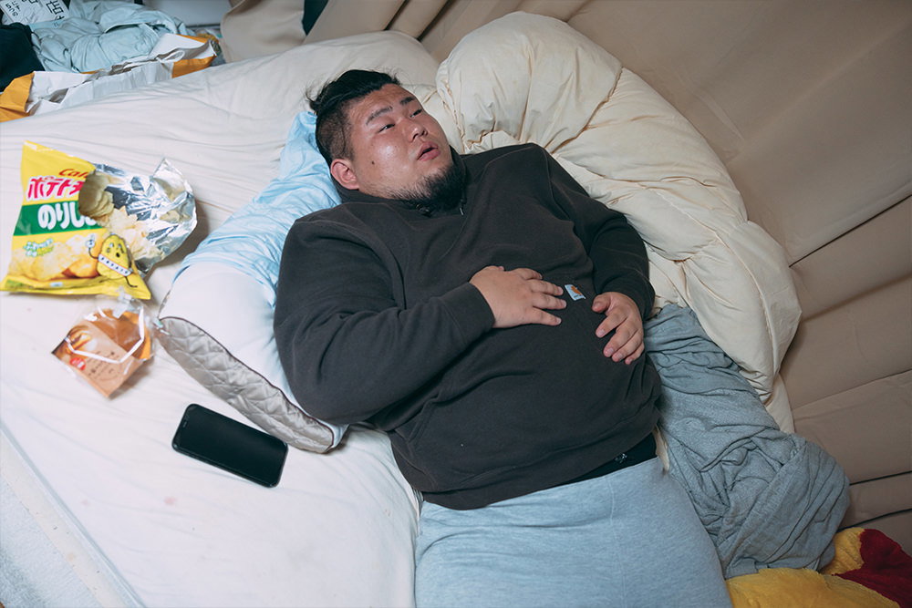 食いすぎてベッドで横になるデブ