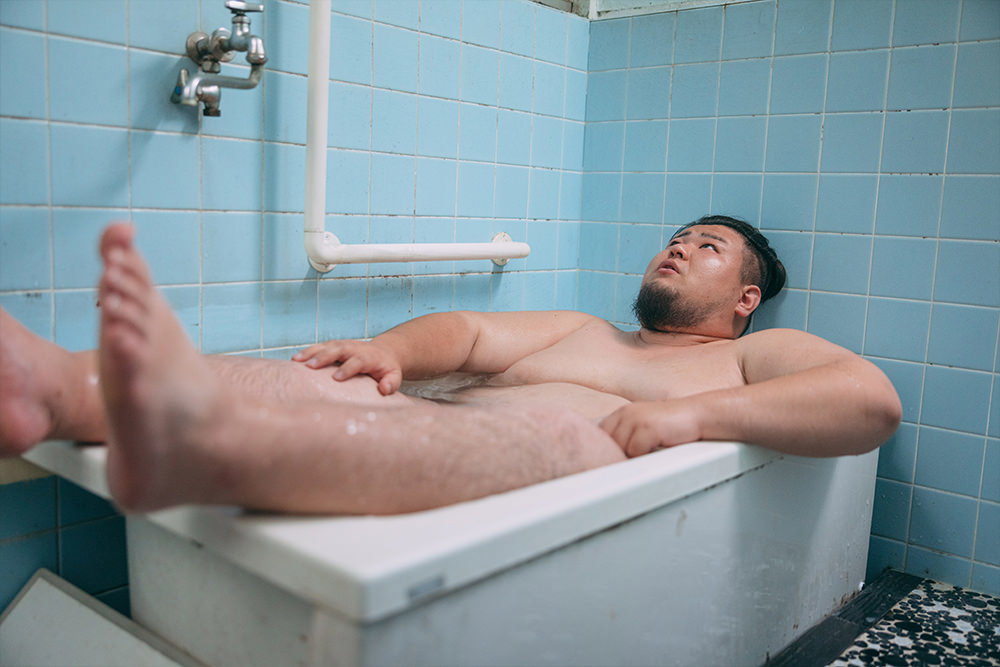 狭い湯船に入り切らないデブ