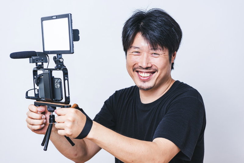 笑顔でスマホを使ってムービー撮影をする男性の写真素材