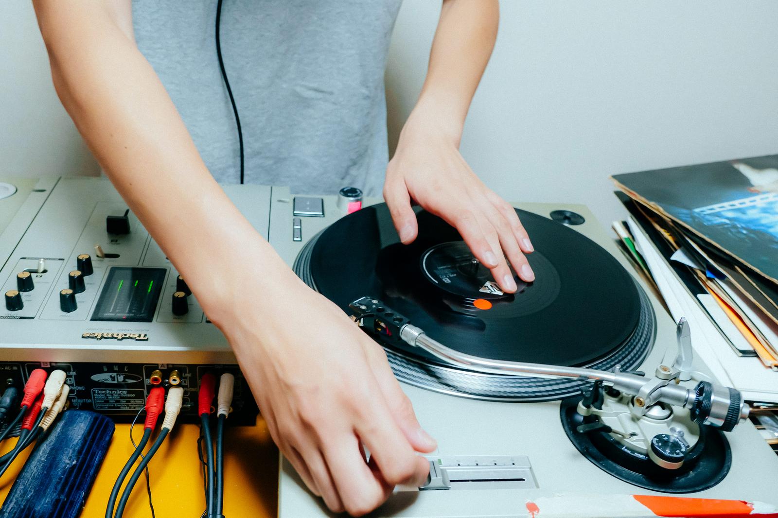 ターンテーブルのレコードに手を置いてDJが操作している様子