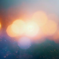 ぼやけた背景に浮かぶ複数の暖かい光点と玉ボケの写真