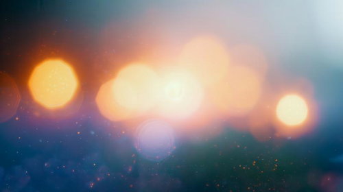 ぼやけた背景に浮かぶ複数の暖かい光点と玉ボケ