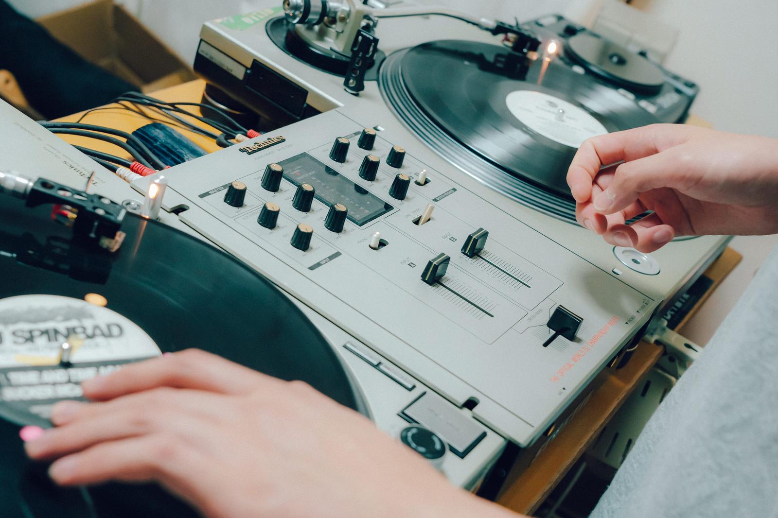 DJがミキサーとターンテーブルを操作する手元