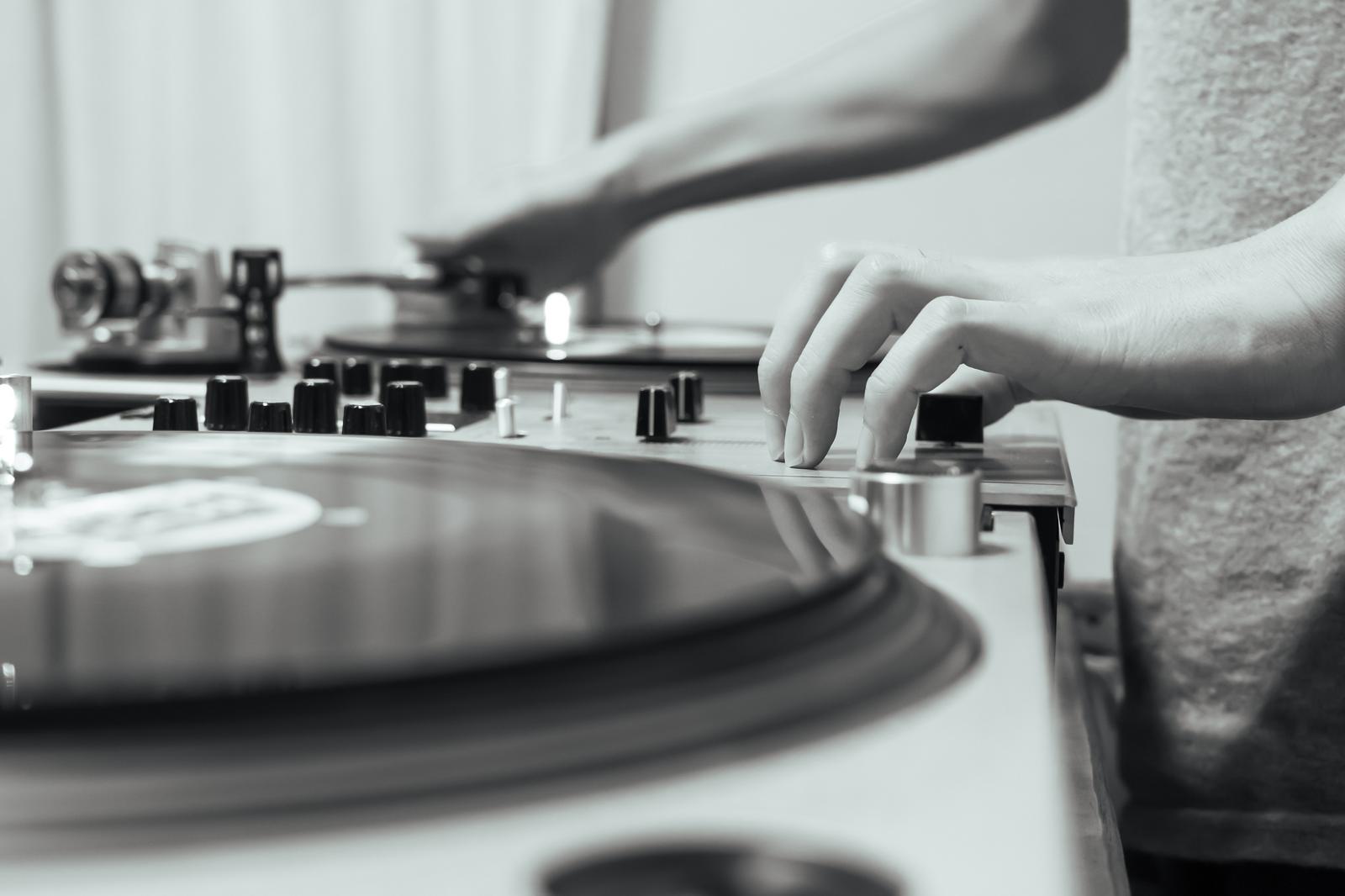 DJがミキサーのスライダーを操作しレコードをプレイしている