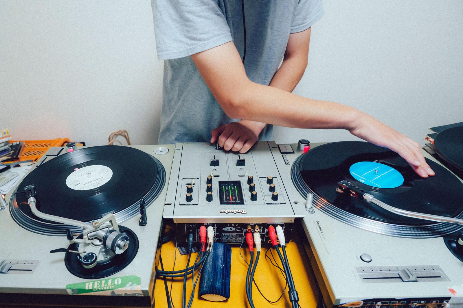 DJがターンテーブルとミキサーを操作してレコードをミックスしている