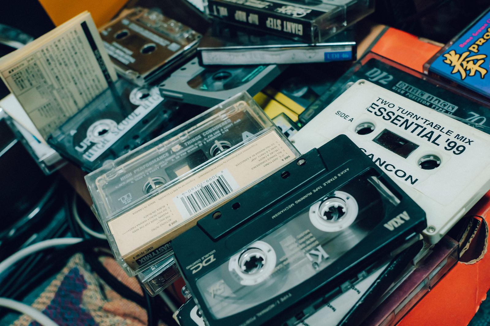 カセットテープ、音楽書籍、DVDケースが雑然と積み重なった写真