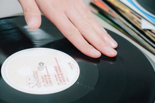 レコード操作中のDJの指先とターンテーブル上のレコード盤
