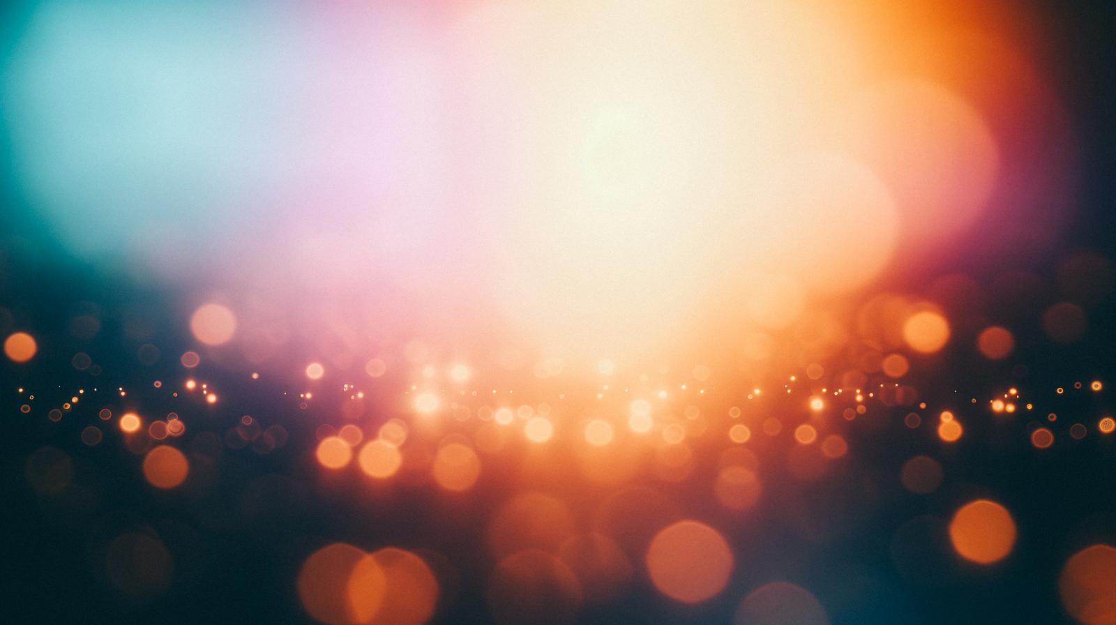 Gradient background transitioning from orange to turquoise blue, with scattered light particles and bokeh orbs