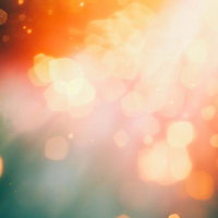 橙色と緑のボケが輝き広がる光のきらめき、玉ボケと光の粒が煌めく抽象背景の写真