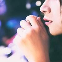 夜景の玉ボケをバックにした寂しげな女性の口元の写真