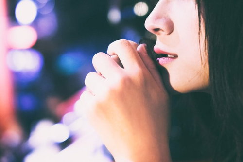 夜景の玉ボケをバックにした寂しげな女性の口元