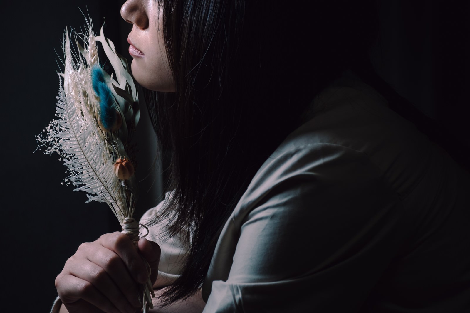 暗い背景でスワッグを手に持つ黒髪の女性の横顔のシルエット