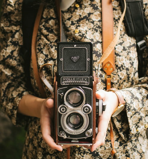 花柄ワンピースを着たオールドカメラを持つ女性の手
