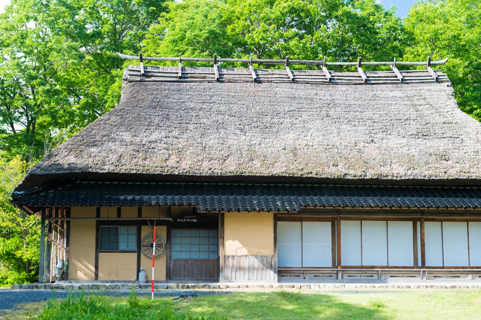 新緑に囲まれた茅葺き屋根の木造古民家