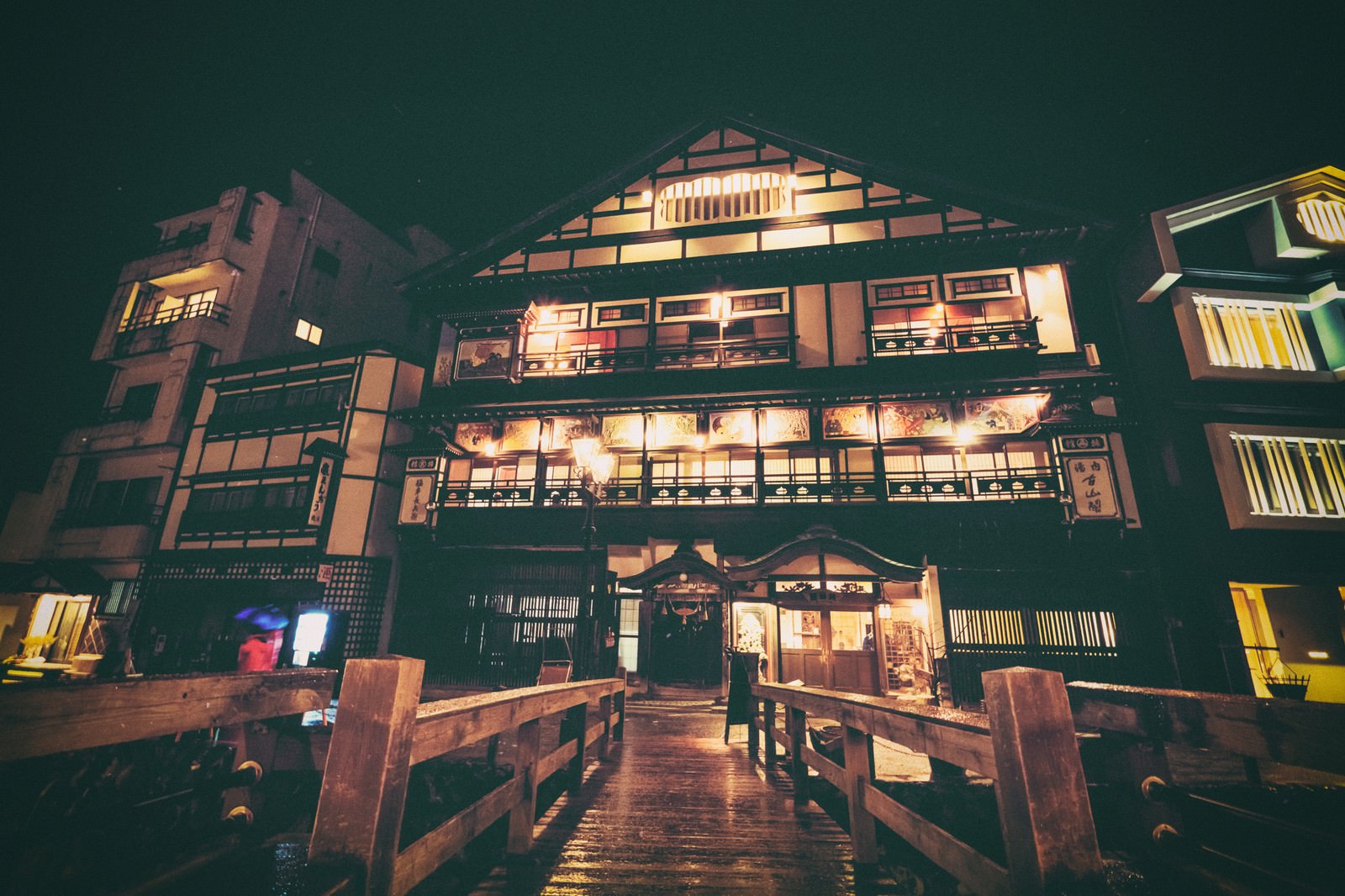夜の銀山温泉街でライトアップされた木造旅館が川を挟んで立ち並ぶ