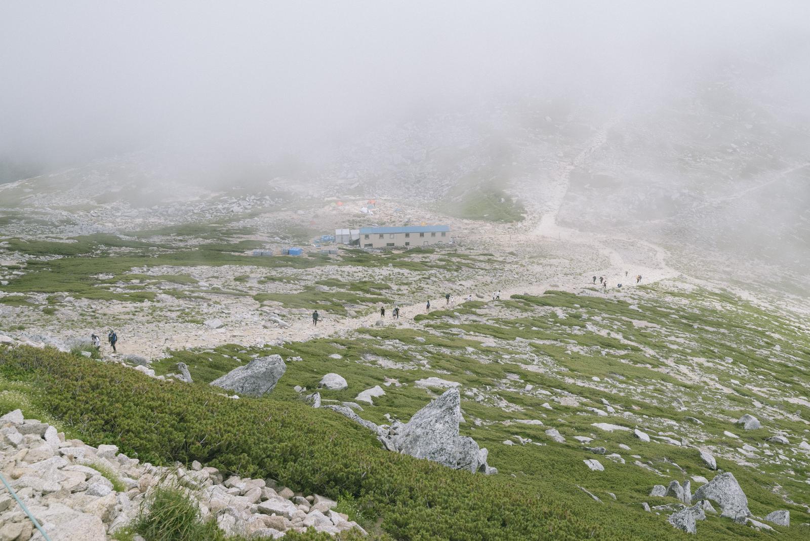 ガスがかかる木曽駒ヶ岳の山頂付近で複数の登山者が登っている風景