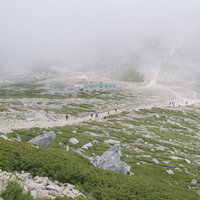 ガスがかかる木曽駒ヶ岳の山頂付近を登る登山者たちの写真