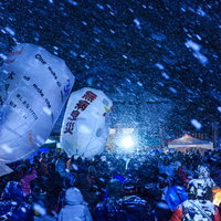 大雪と人混みと青く光る紙風船の夜間イベントの写真