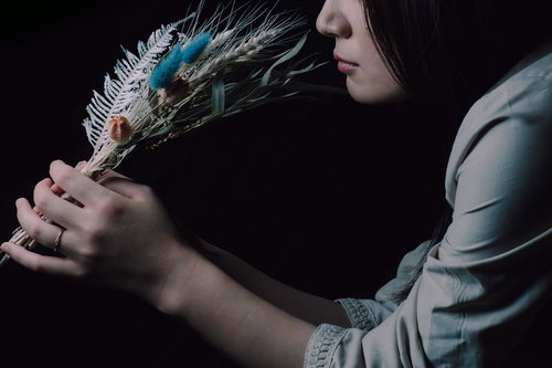 手に持つスワッグを嗅ぐ女性の横顔、花の香りを楽しむ瞬間