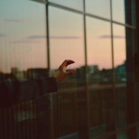 左手で「C」のジェスチャーを示す夕暮れの窓辺の写真