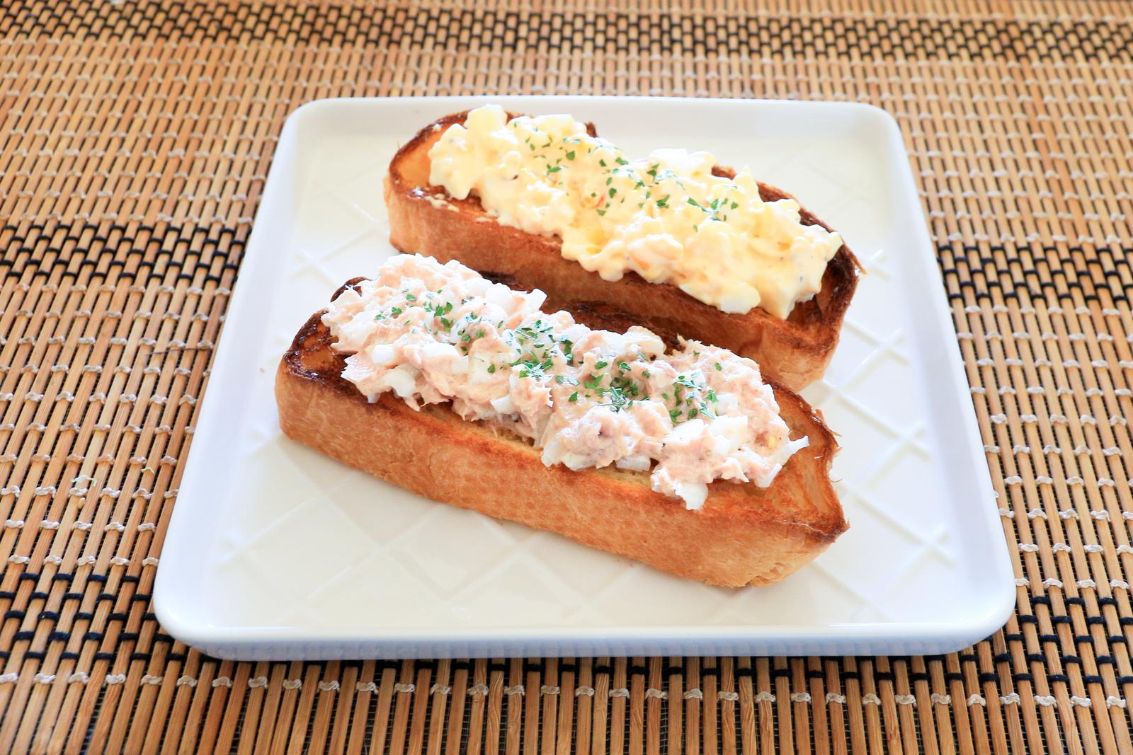 Two tuna mayo and egg mayo open sandwiches served on a white plate