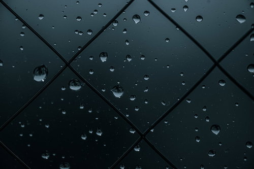 薄暗い窓ガラスに付着した水滴