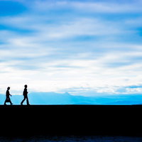 青空と埠頭を歩く親子のシルエットの写真