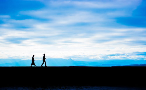 青空と埠頭を歩く親子のシルエット