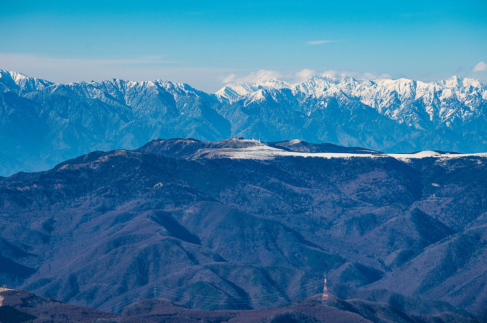 青空の下に雪化粧した美ヶ原とアルプス山脈が層状に連なる冬景色