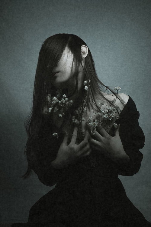 前髪で顔を隠すように俯く、悲しい気持ちを抱く女性