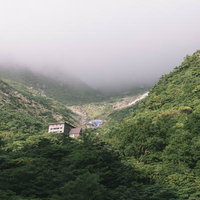 くろがね小屋にかかる雲と緑に包まれた安達太良山の谷間の写真