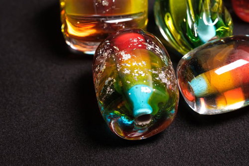 黒い背景に無造作に置かれた色とりどりのとんぼ玉