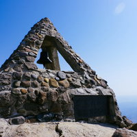 晴天の空のもとの岩木山山頂の碑と鐘、津軽富士の頂上の写真