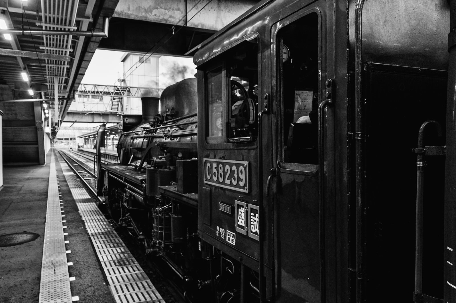 駅のホームに停車している蒸気機関車のモノクロ写真