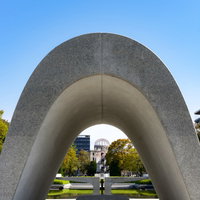 広島平和記念公園の原爆死没者慰霊碑と平和の灯の写真