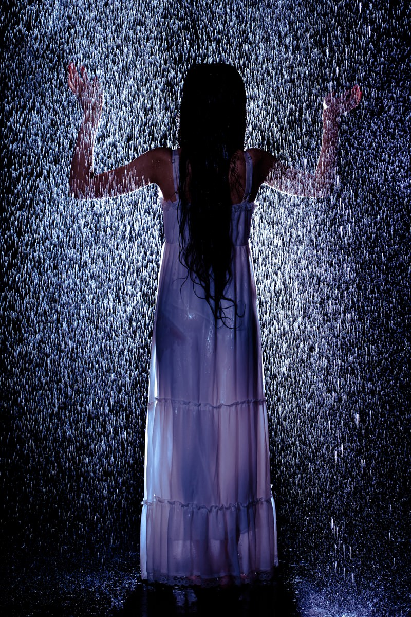 豪雨の中で両腕を広げて立つ女性のシルエット［モデル：緋真煉］