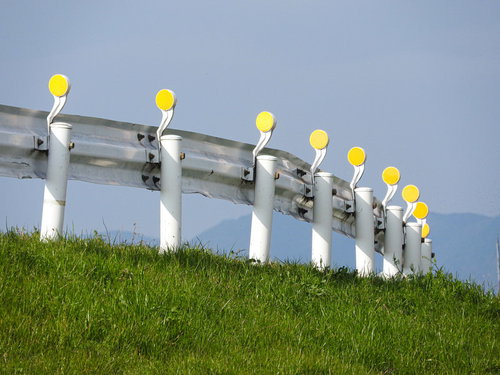 道路カーブに設置されたガードレールの裏側と黄色の反射板