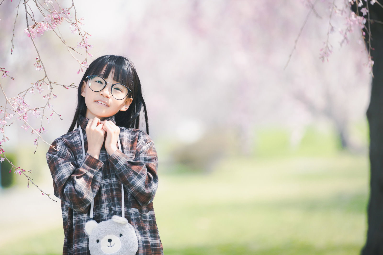 桜の木の前で手を顔に添えてポーズをとる制服姿の女の子［モデル：あんじゅ］