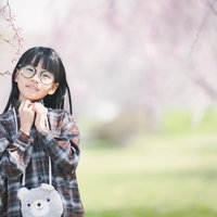 春の桜の下でポーズをとる制服姿の女の子の入学式写真の写真