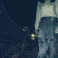 暗闇を徘徊する白い服の女性のホラー写真の写真