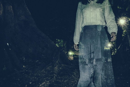 暗闇を徘徊する白い服の女性のホラー写真