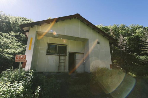 白根山避難小屋と樹林に囲まれた山道の登山風景