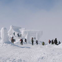 冬の刈田岳山頂に立つ登山者たちと雪の造形物の写真